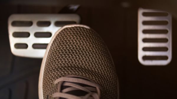 Eine Person trägt Sportschuhe beim Bedienen der Pedale im Auto.