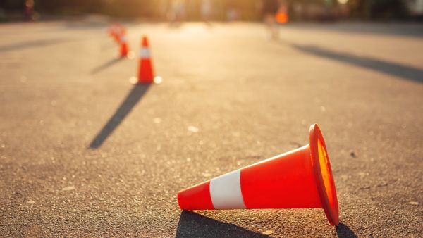 Auf dem Bild liegt ein umgefallener Verkehrskegel auf dem Asphalt eines Übungsplatzes für Fahrsicherheitstraining.