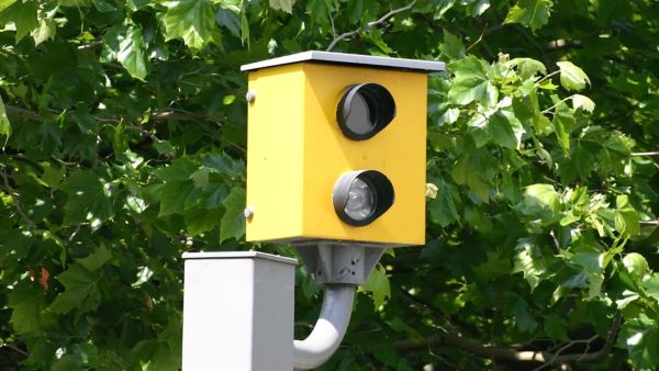 Eine gelbe Radarkamera mit zwei Objektiven steht am Straßenrand und erfasst Geschwindigkeiten zur Verkehrsanalyse.