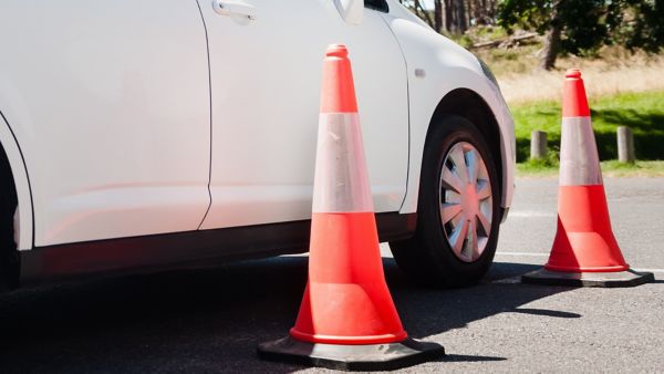 Zwei rote Zylinder stehen neben weißem Auto