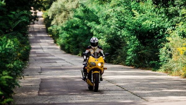 Eine Person fährt ein Motorrad durch eine grüne Landschaft, wie es mit der Führerscheinklasse A oder A2 erlaubt ist.