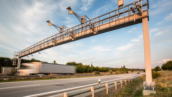 Eine moderne Erfassungsbrücke mit Kameras über einer Autobahn wird zur automatischen Kontrolle von Fahrzeugen im Rahmen der Mauterhebung genutzt.