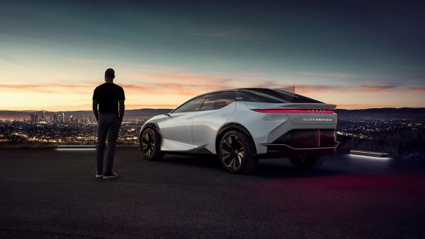 Eine Person steht neben einem geparkten Lexus und blickt auf eine Stadt