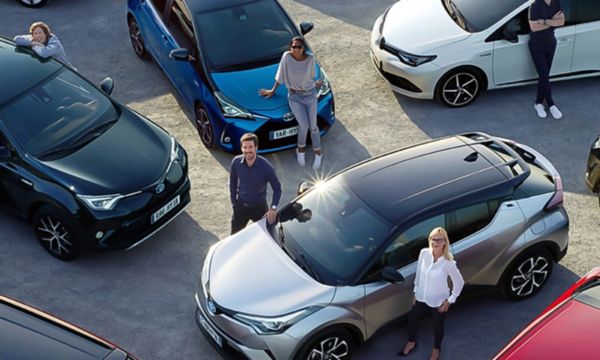 Luftaufnahme einer Gruppe von Fahrerinnen und Fahrern mit ihren Toyota Fahrzeugen, zusammen geparkt auf einer Schotterfläche