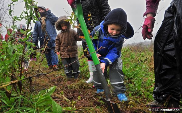 Ein Kindergarten Kind beim Schaufeln während eines Toyota Umweltschutzprojektes. Im Hintergrund sind weitere Kinder, die zuschauen.