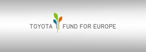 Das Bild zeigt das Logo des „Toyota Fund for Europe“, das stilisierte grüne und blaue pflanzenähnliche Elemente enthält, die Wachstum und Nachhaltigkeit symbolisieren. Der Text „TOYOTA FUND FOR EUROPE“ ist in einer modernen, klaren Schriftart gehalten, die das Engagement der Organisation für Umweltinitiativen und die Unterstützung der Gemeinschaft widerspiegelt.