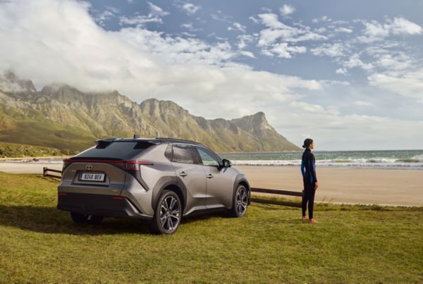 Frau am Strand mit einem Toyota bZ4X