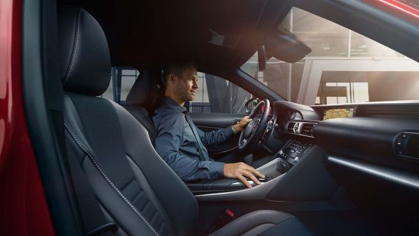 Eine Person am Steuer eines Lexus, die sich auf die Straße konzentriert, während ein GPS-Navigationsbildschirm eine Karte im Armaturenbrett anzeigt.