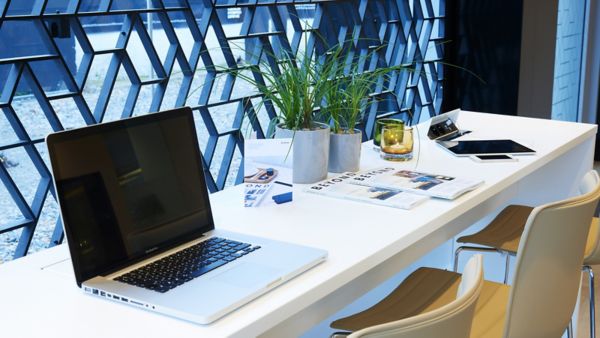 Ein aufgeklappter Laptop auf einem Tisch mit Broschüren daneben