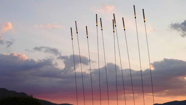 Eine Reihe von freistehende Lampen vor einem Abendhimmel, die an Schilfrohre erinnern