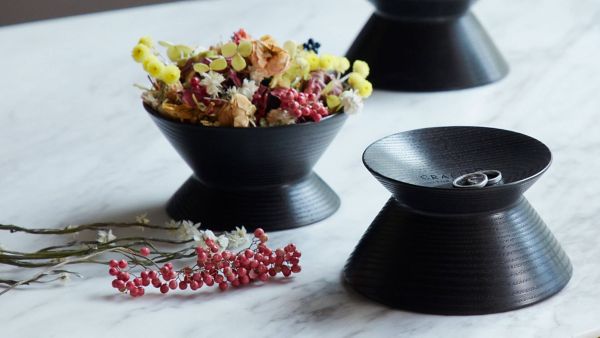 Filigrane, schwarze Schalen aus Holz, gefüllt mit Blumen und Schmuck