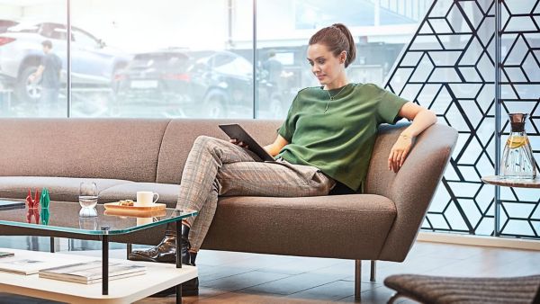 Frau sitzt mit Tablet in der Hand in einem Lexus Autohaus