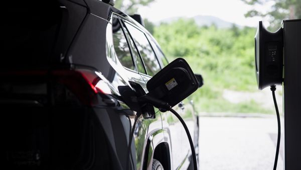 Schwarzes Elektroauto wird in einer Garage an einer Ladesäule aufgeladen