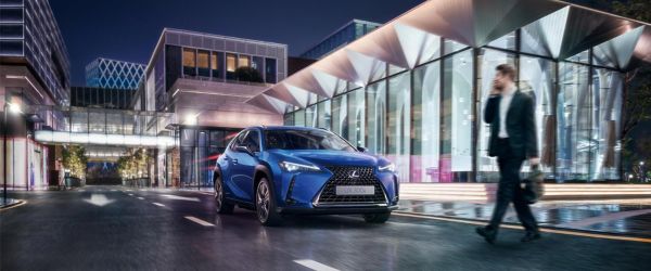 Mann überquert eine Straße vor einem Lexus UX 300e