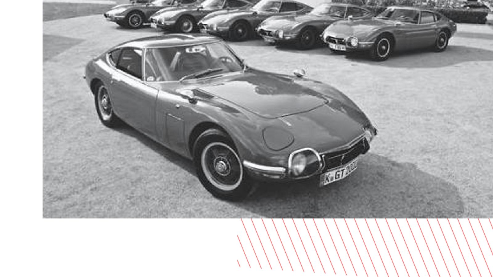 Klassisches Schwarz-Weiß-Foto mit einem Oldtimer-Sportwagen von Toyota im Vordergrund, umgeben von mehreren Oldtimern in einer Showkulisse.