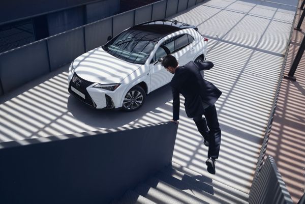 Eine Person spurtet eine Treppe hinunter zu einem weißen Lexus, der in einer Einfahrt steht
