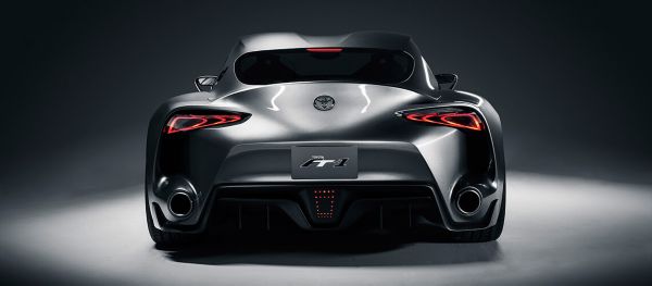 Rückansicht eines schwarz-silbernen Toyota FT1 von oben beleuchtet, mit markanten rot leuchtenden Rückleuchten und zwei großen Auspuffrohren