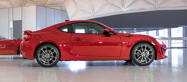 Seitenansicht eines roten Toyota GT86 mit sportlicher Silhouette in einer hellen Ausstellungshalle