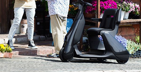 Ein Elektromobil steht neben zwei sich unterhaltenden Personen