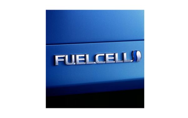 Nahaufnahme eines silbernen Fuelcell Logos auf blauer Karosserie.