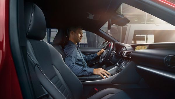 Ein Fahrer, der sich auf die Straße konzentriert, während er auf dem Fahrersitz eines modernen Lexus sitzt, der ein elegantes Innenraum- und Armaturenbrettdesign aufweist.