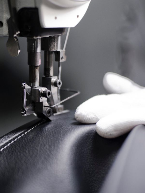 Eine Hand mit Handschuh eines Lexus Takumi Handwerkers an einer Nähmaschine in Nahaufnahme 