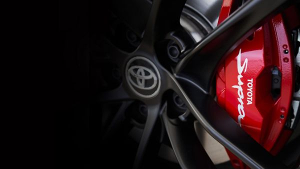 Detailaufnahme einer schwarzen Felge mit Toyota Logo in der Mitte und einem roten Bremssattel mit Schriftzug „Toyota Supra“