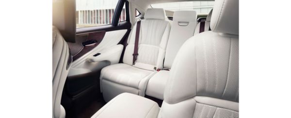 Geräumiger und luxuriöser Rücksitz eines Lexus LS, mit weißem Lederbezug mit perforierten Details und einem Sicherheitsgurt