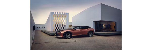 Ein eleganter Lexus RZ ist vor einem modernen Haus geparkt und an eine Ladestation angeschlossen, die zeitgenössische Architektur und einen minimalistischen Stil präsentiert.