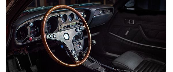 Cockpit des Toyota Celica von 1974 mit Holzlenkrad, schwarzen Armaturen und Sitzen