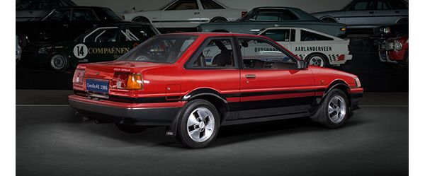 Toyota Corolla AE aus dem Jahr 1986 schräg von hinten im Spot-Licht in einer abgedunkelten Ausstellungshalle, im Hintergrund weitere Fahrzeuge