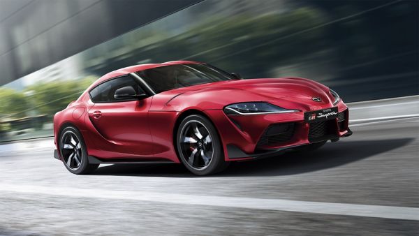 Roter Toyota GR Supra von der Seite. Der Hintergrund ist aufgrund der Geschwindigkeit verschwommen