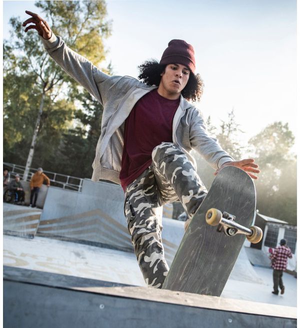 Junger Mann macht mit seinem Skateboard einen Trick auf der Halfpipe