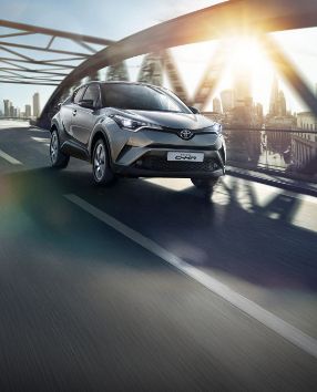 Toyota C-HR przejeżdża przez wiadukt nad miastem.