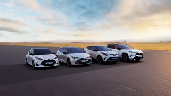 Vier weiße Hybridautos von Toyota stehen nebeneinander im Sonnenuntergang und symbolisieren die breite Palette von Hybridautos bei Toyota