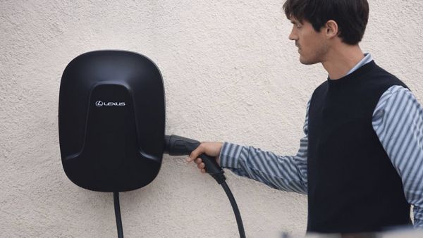 Eine Person entnimmt das Ladekabel aus einer Lexus Wallbox