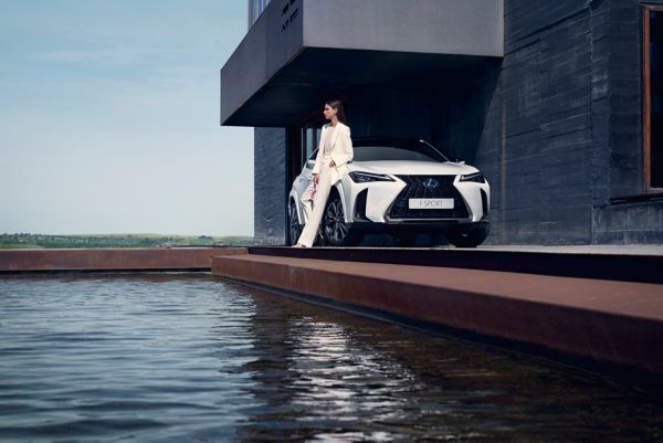 Eine Person lehnt lässig an einem weißen Lexus, der neben einem Pool geparkt ist