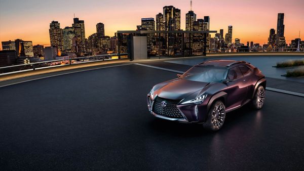 Ein dunkelrotes Lexus UX Konzeptfahrzeug steht auf einem Dach vor einer Stadt-Silhouette