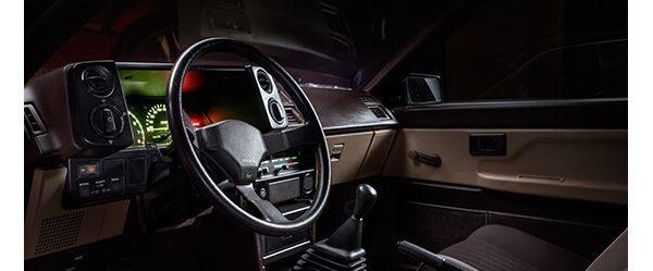 Cockpit des Toyota Corolla AE von 1986 mit Drei-Speichen-Lenkrad, schwarzen Armaturen und grün leuchtenden Instrumenten
