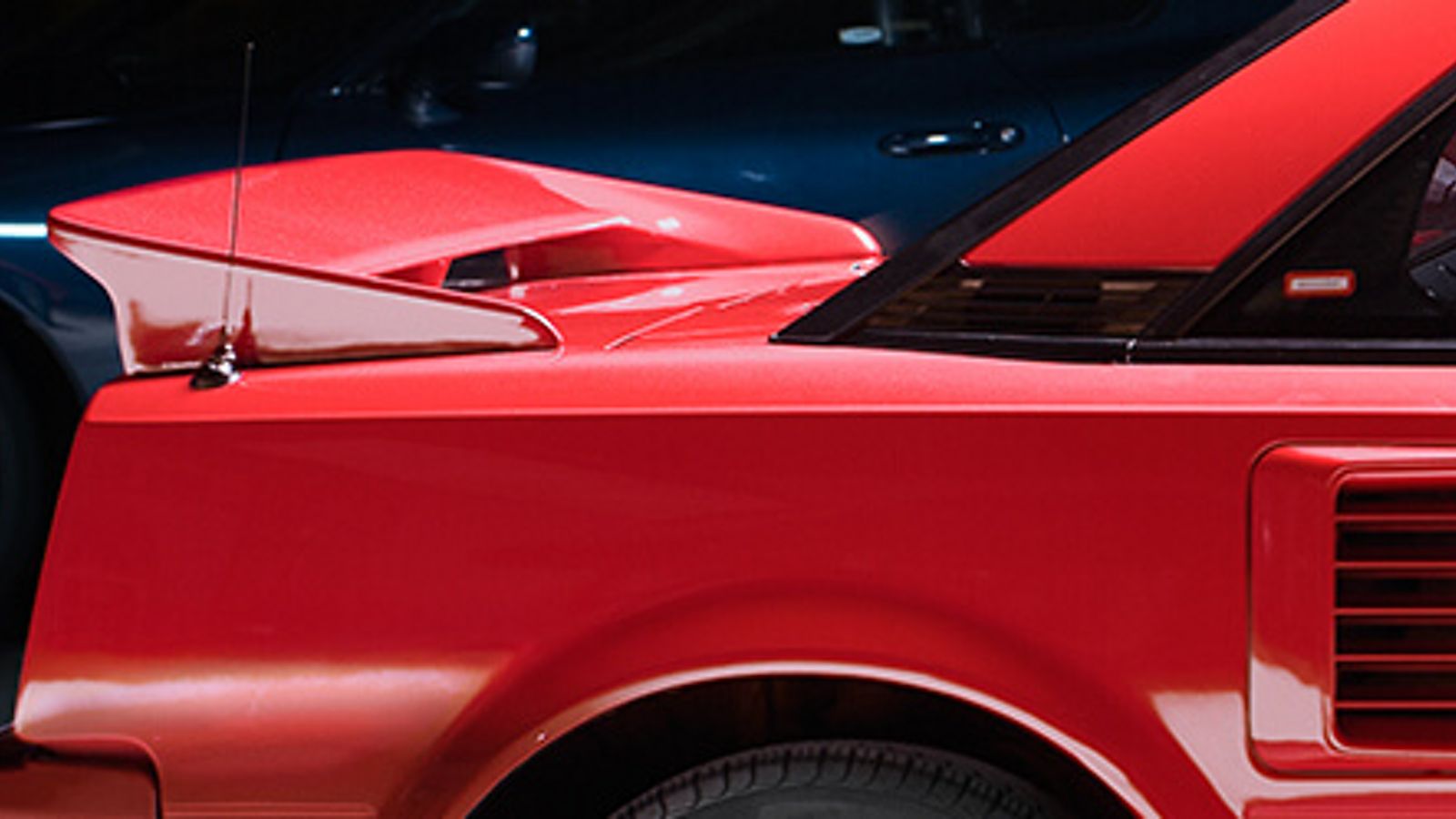 Seitliche Nahaufnahme der Heckpartie eines roten Toyota MR2 mit Spoiler und Lüftungsschlitzen