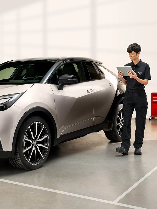 Une employée du service Toyota inspecte un véhicule en utilisant une tablette pour vérifier les informations.