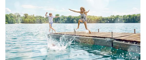 Kinder auf einem Steg springen ins Wasser