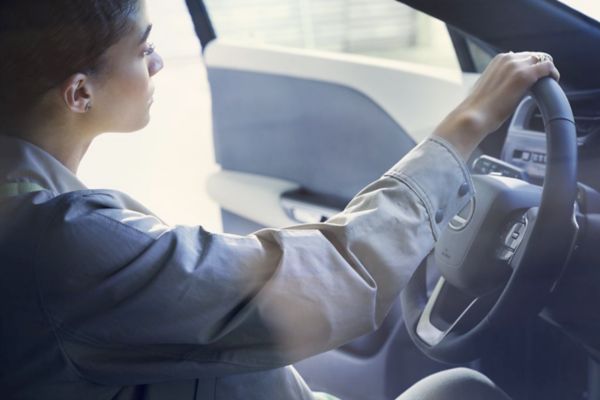 Eine Person sitzt in einem Lexus mit einer Hand am Lenkrad bei geöffneter Tür