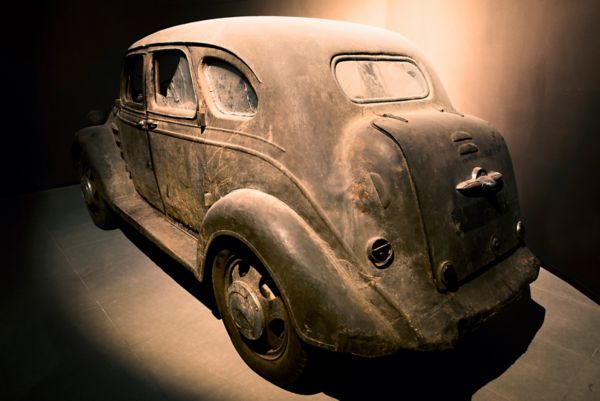 Extrem verwitterter und staubiger Toyoda AA von 1936 mit teilweise zerbrochenen Scheiben von schräg hinten in einem gefliesten Ausstellungsraum