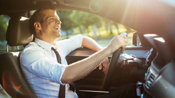 lächelnder Mann sitzt am Steuer eines Autos