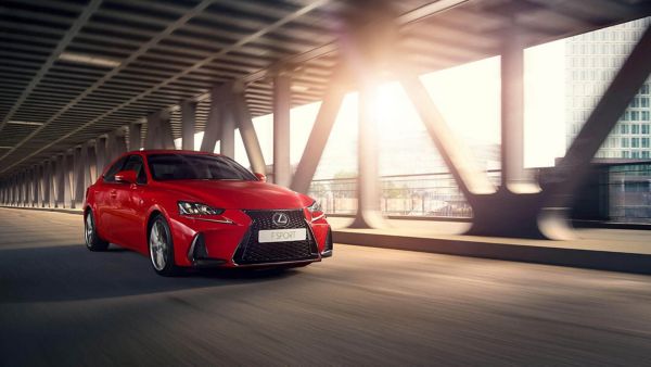 Ein roter Lexus F Sport fährt unter einer Brücke entlang