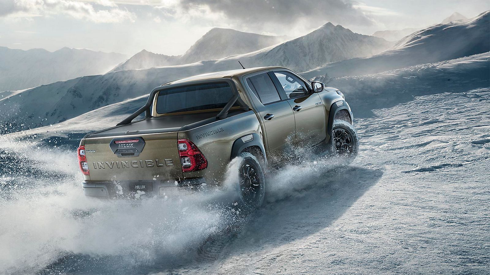 Brauner Toyota Hilux fährt einen schneebedeckten Berg hoch