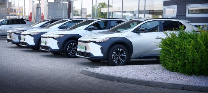 Rząd zaparkowanych modeli Toyoty pod salonem.