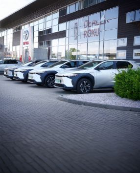 Rząd zaparkowanych modeli Toyoty pod salonem.