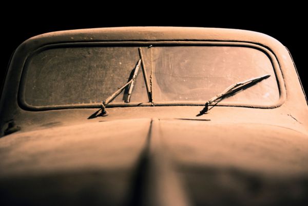 Staubige Windschutzscheibe des Toyoda AA mit teilweise schief stehenden Scheibenwischern, im Vordergrund unscharf die lange Motorhaube